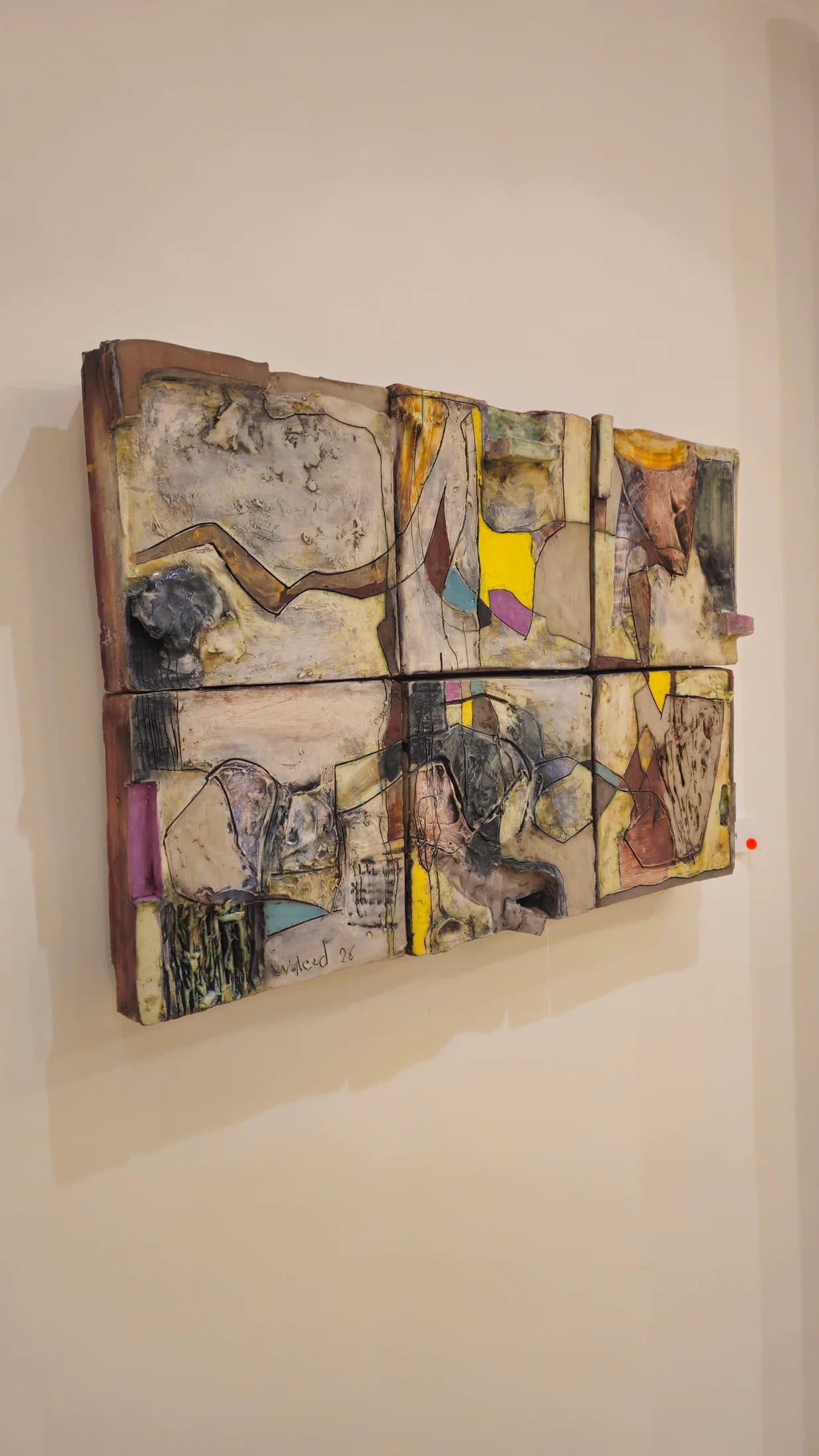 Six-panel relief in mixed media — incised lines, inscribed fragments, flashes of yellow and teal.